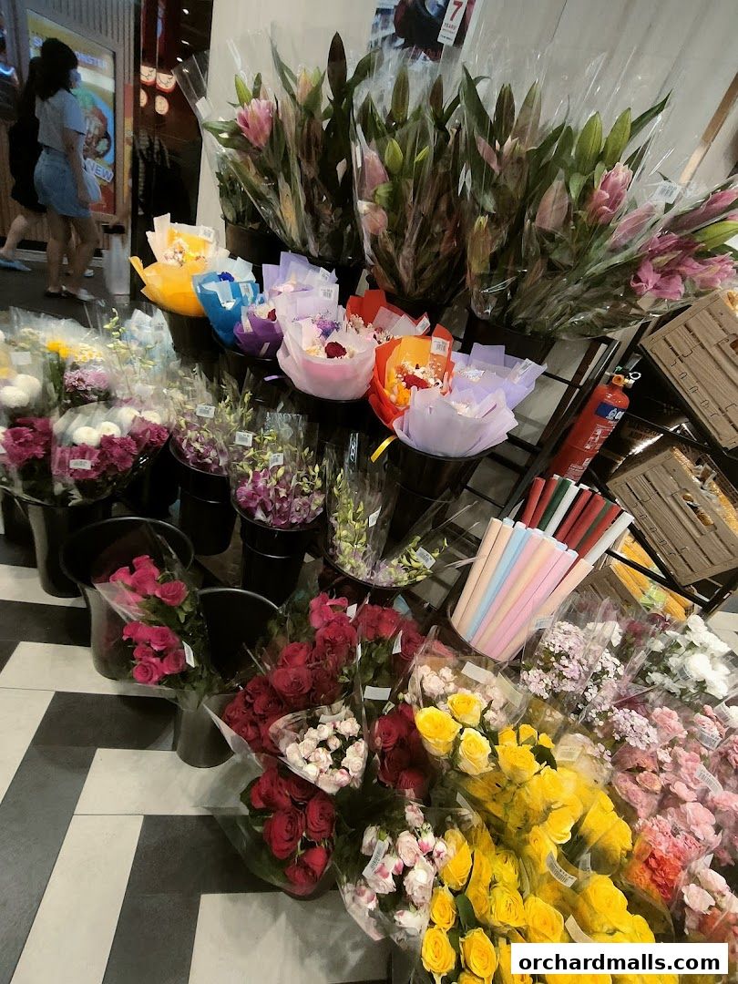 A vibrant display of fresh flowers, including roses and lilies, arranged in buckets.