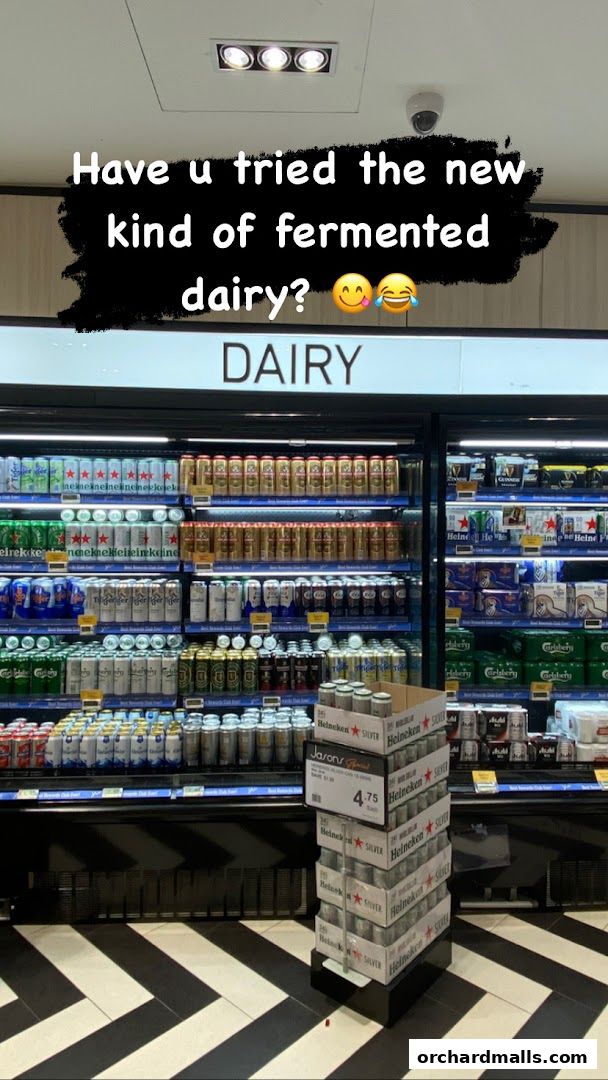A display of various canned beverages in a refrigerated section labeled 'DAIRY'.