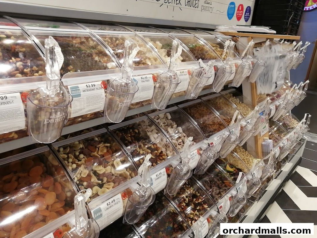 A display of bulk dried fruits and nuts in clear bins with scoops.