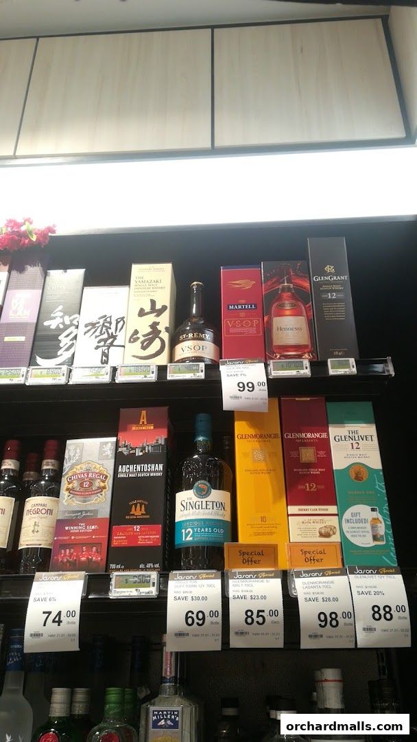 A selection of premium whiskies and cognacs displayed on shelves with price tags.