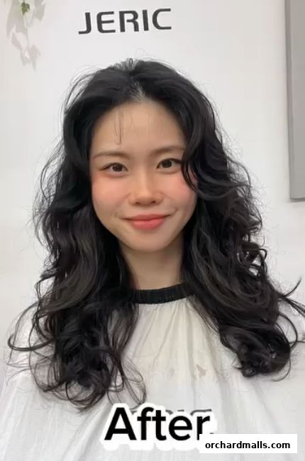 A woman with styled wavy dark hair smiles after a salon treatment.