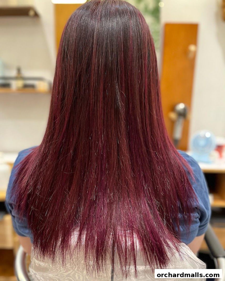 A person's back with long, straight, dark hair with subtle red highlights.