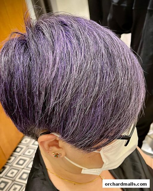 A close-up of a person's short, layered hair with purple and silver highlights.