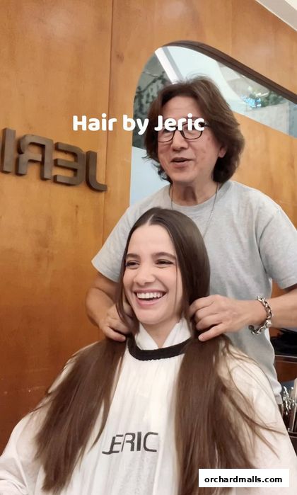 A stylist works on a smiling woman's hair inside a salon.