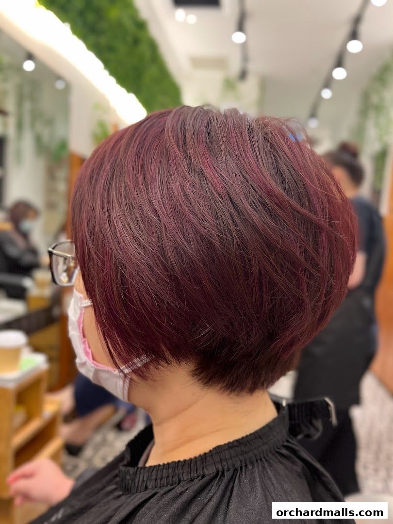 A woman with a stylish burgundy bob haircut at a salon.