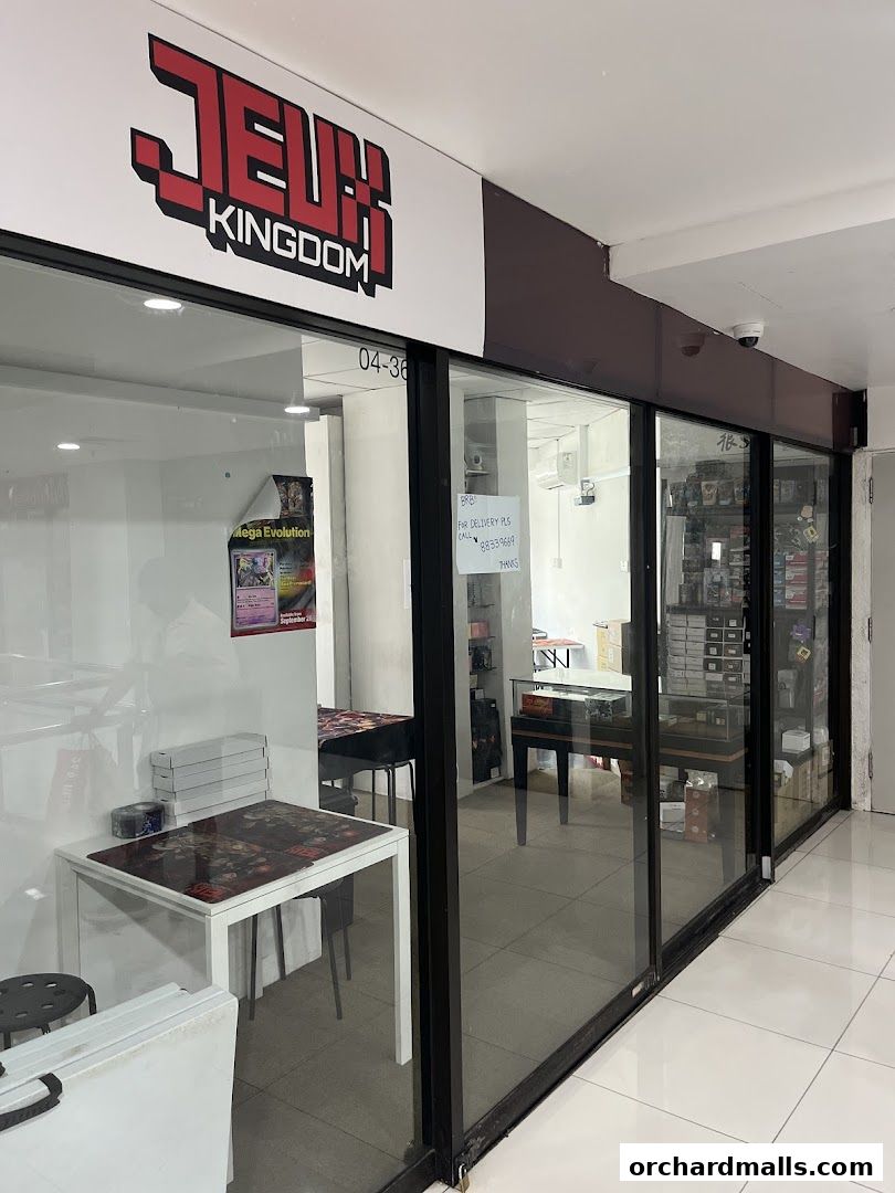 Exterior view of Jeux Kingdom, a shop selling games and collectibles, with display tables and shelves visible.
