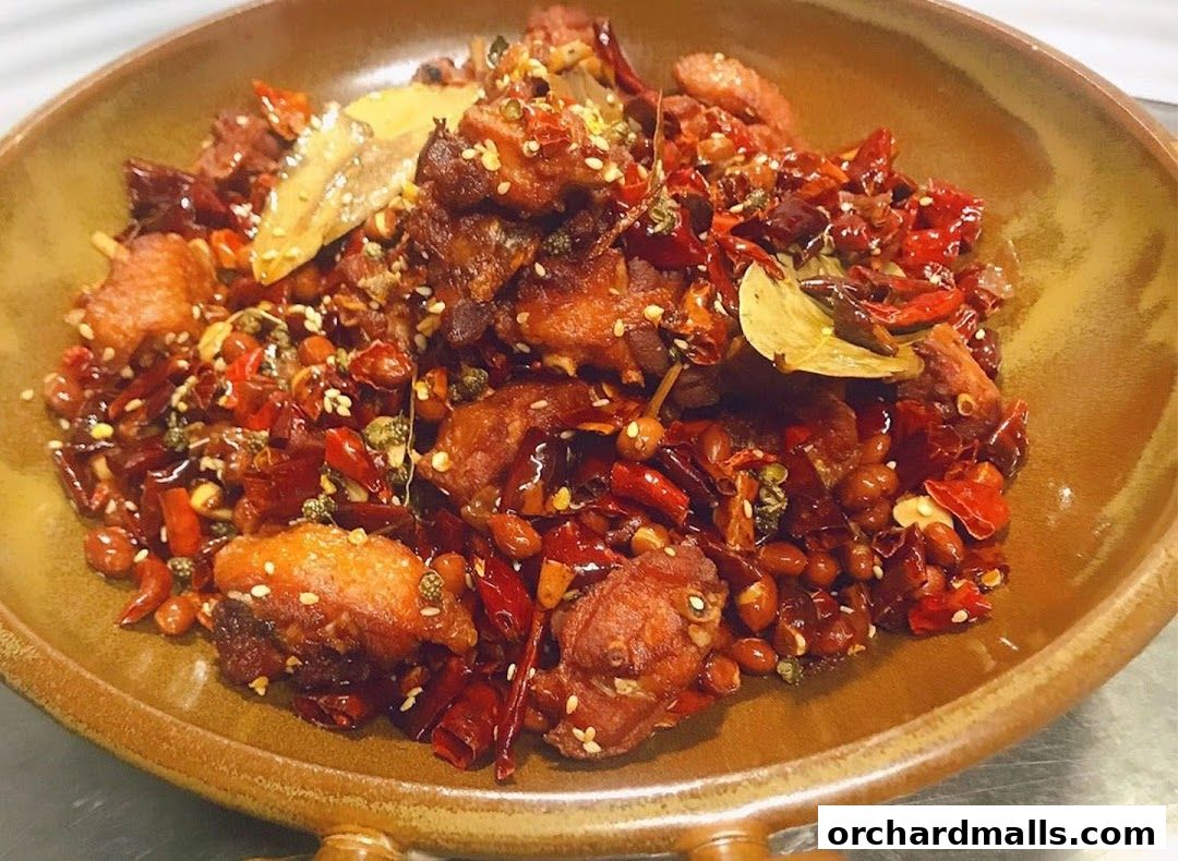 A close-up shot of a spicy Sichuan dish with fried chicken, chili peppers, and peanuts.