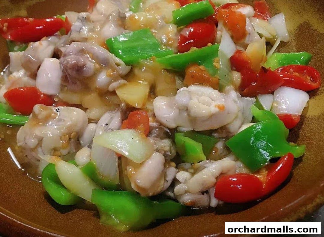 A close-up of a delicious stir-fried dish with frog meat, peppers, and onions.