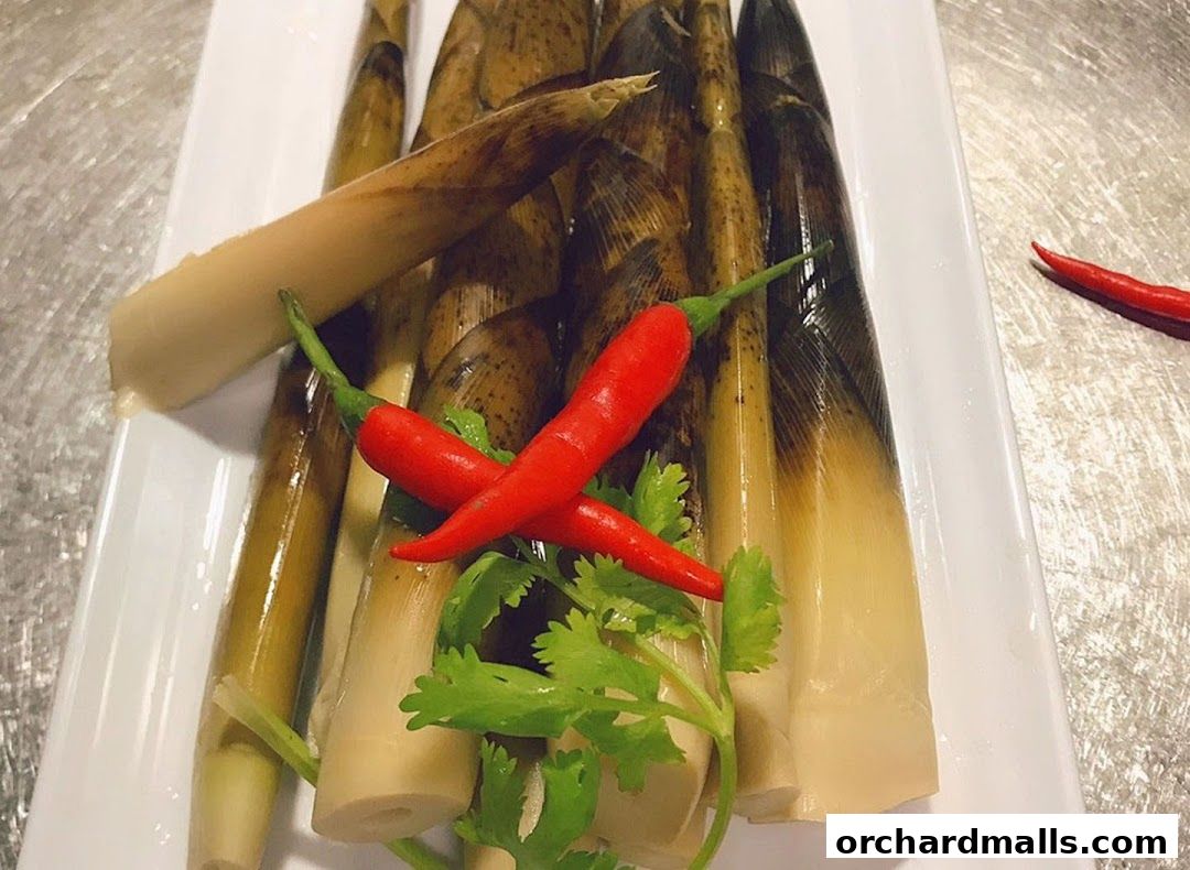 A white platter filled with fresh bamboo shoots, garnished with red chilies and cilantro.