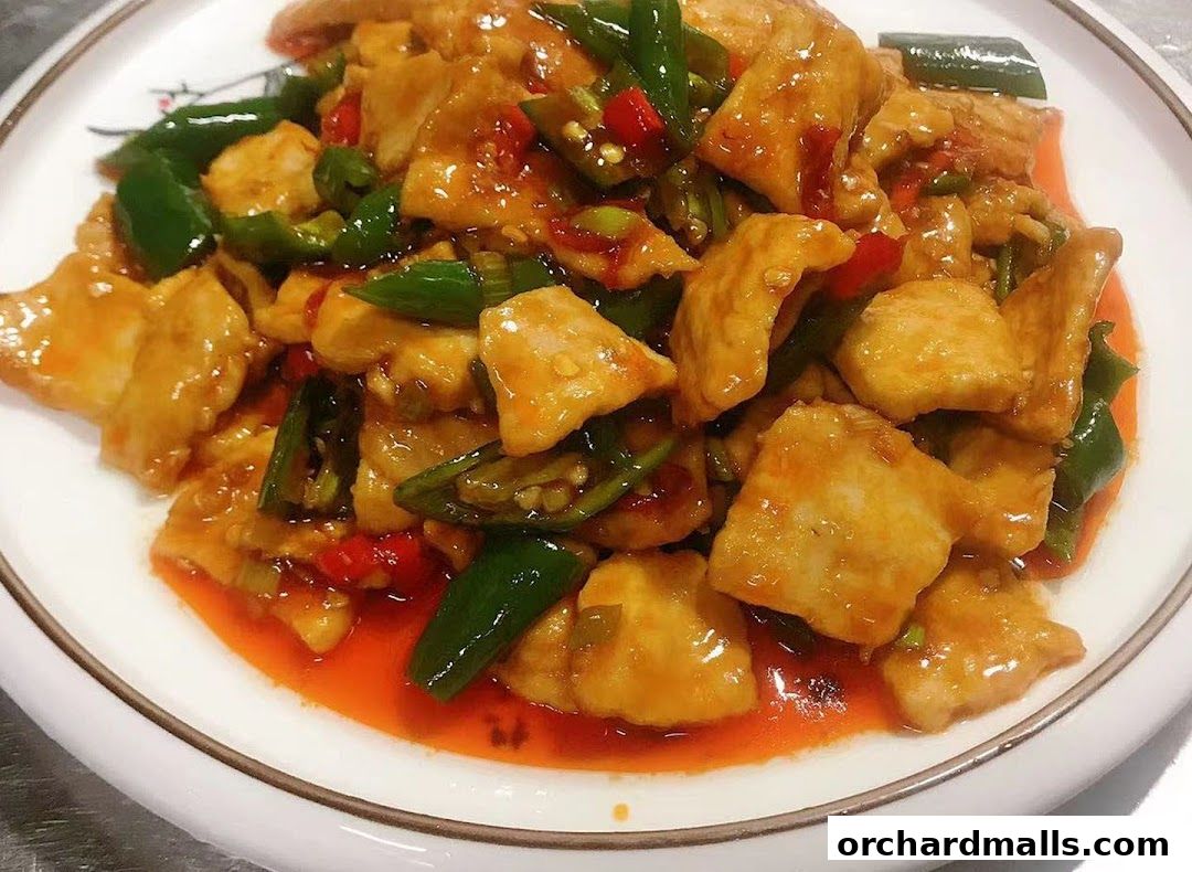 A plate of stir-fried chicken with green and red peppers in a savory sauce.