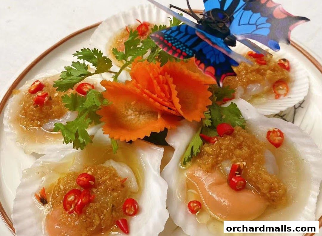 Steamed scallops topped with garlic, chili, and cilantro, garnished with carrot and a butterfly.