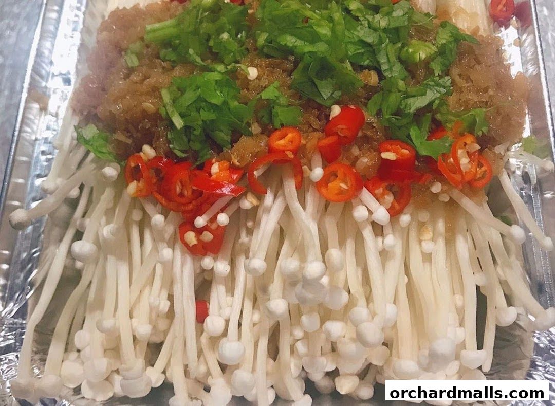 A close-up of enoki mushrooms topped with minced garlic, chili, and cilantro.