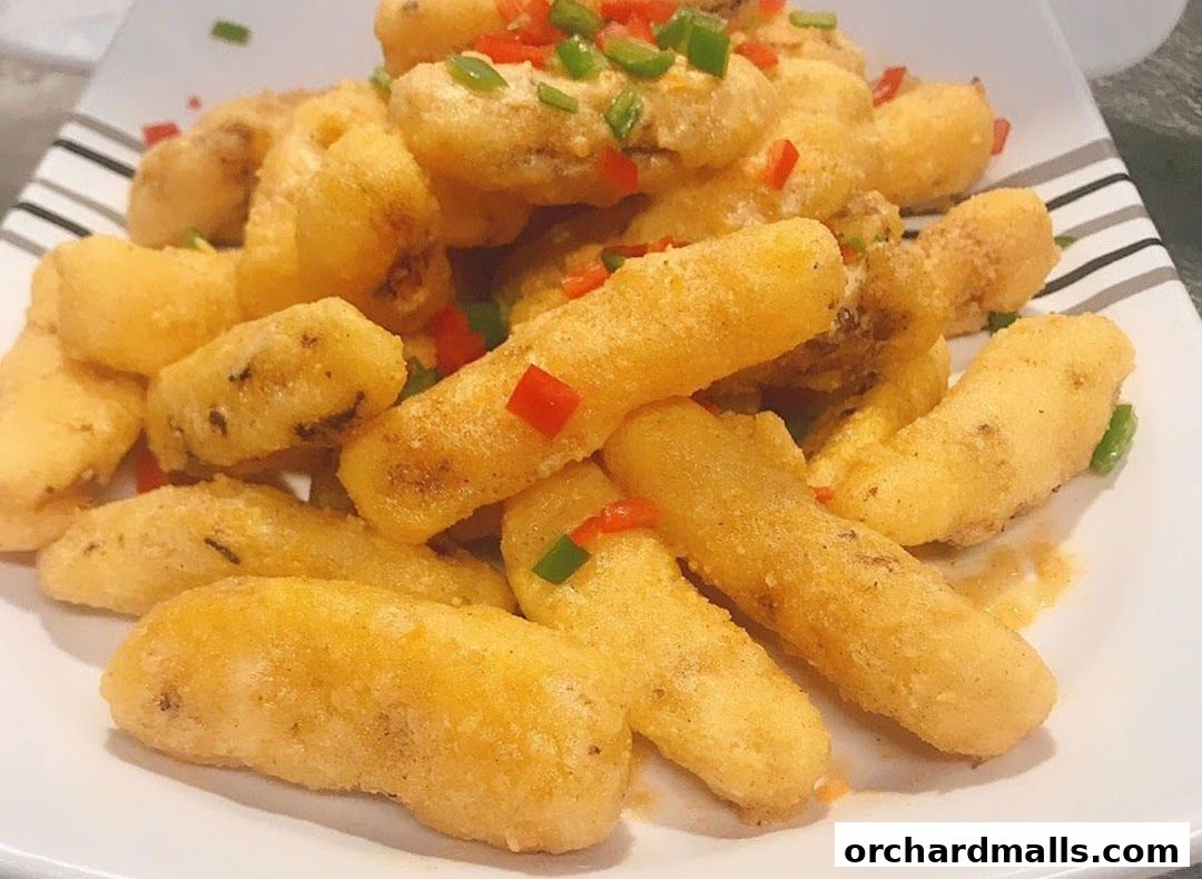 A plate of golden-fried, crispy snacks topped with diced red and green peppers.
