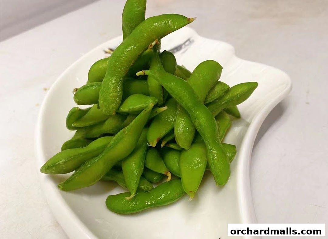 A white plate filled with fresh, vibrant green edamame pods.