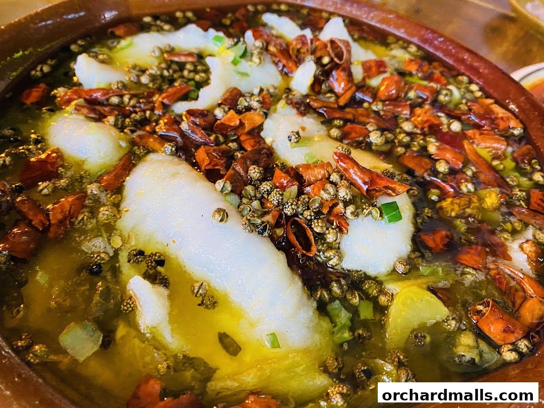 A close-up shot of a spicy fish dish with chili peppers and Sichuan peppercorns.