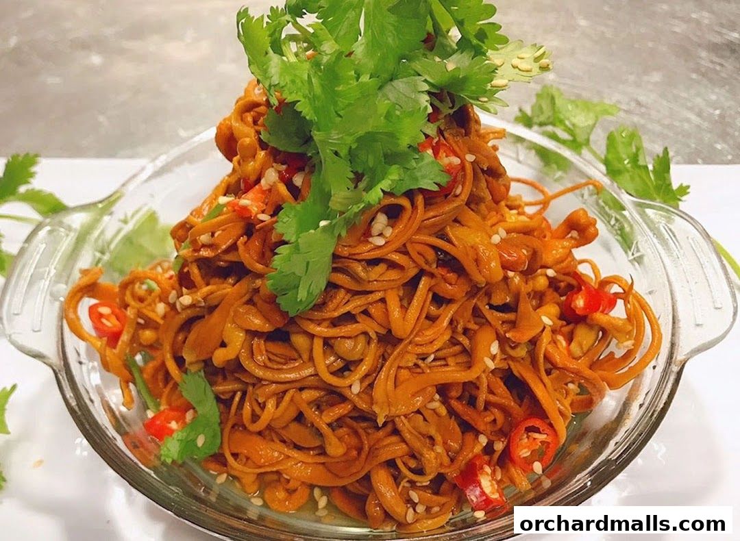 A close-up of a delicious dish with noodles, chili, and cilantro in a glass bowl.