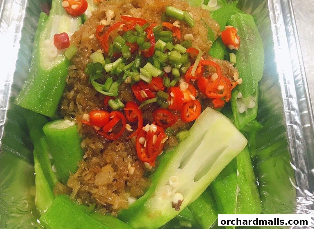 A close-up of steamed okra topped with minced garlic, chili, and scallions.