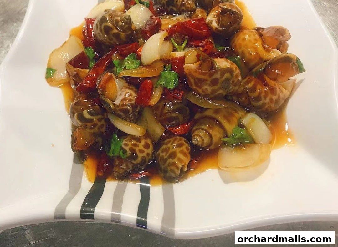 A plate of spicy snails with chili peppers, garlic, and herbs.