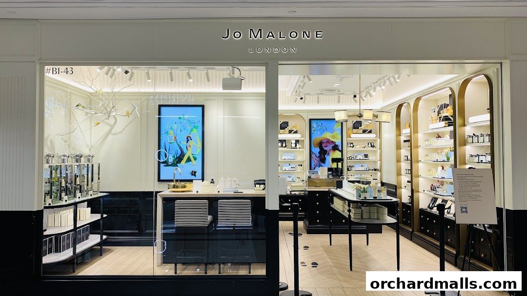 The elegant Jo Malone London shop front displays perfumes and gift sets on illuminated shelves.