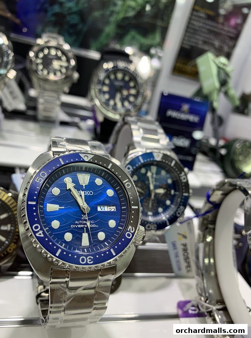 Close-up of several Seiko automatic diver watches with blue dials on display.