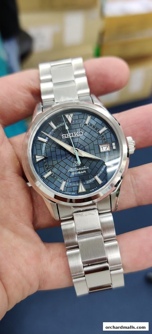 A close-up shot of a Seiko automatic watch with a blue patterned dial.