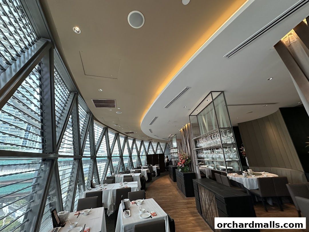 Interior of a restaurant with tables set for dining and large windows offering city views.