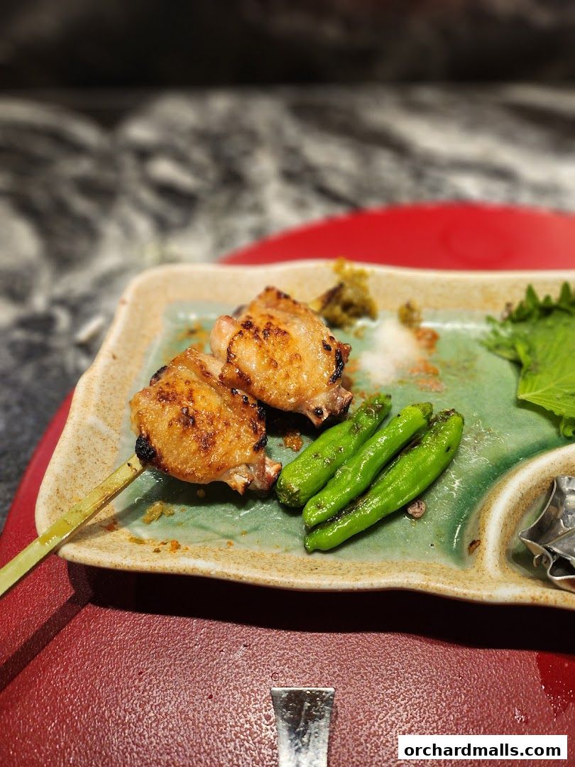 Delicious grilled chicken skewers with shishito peppers served on a plate.