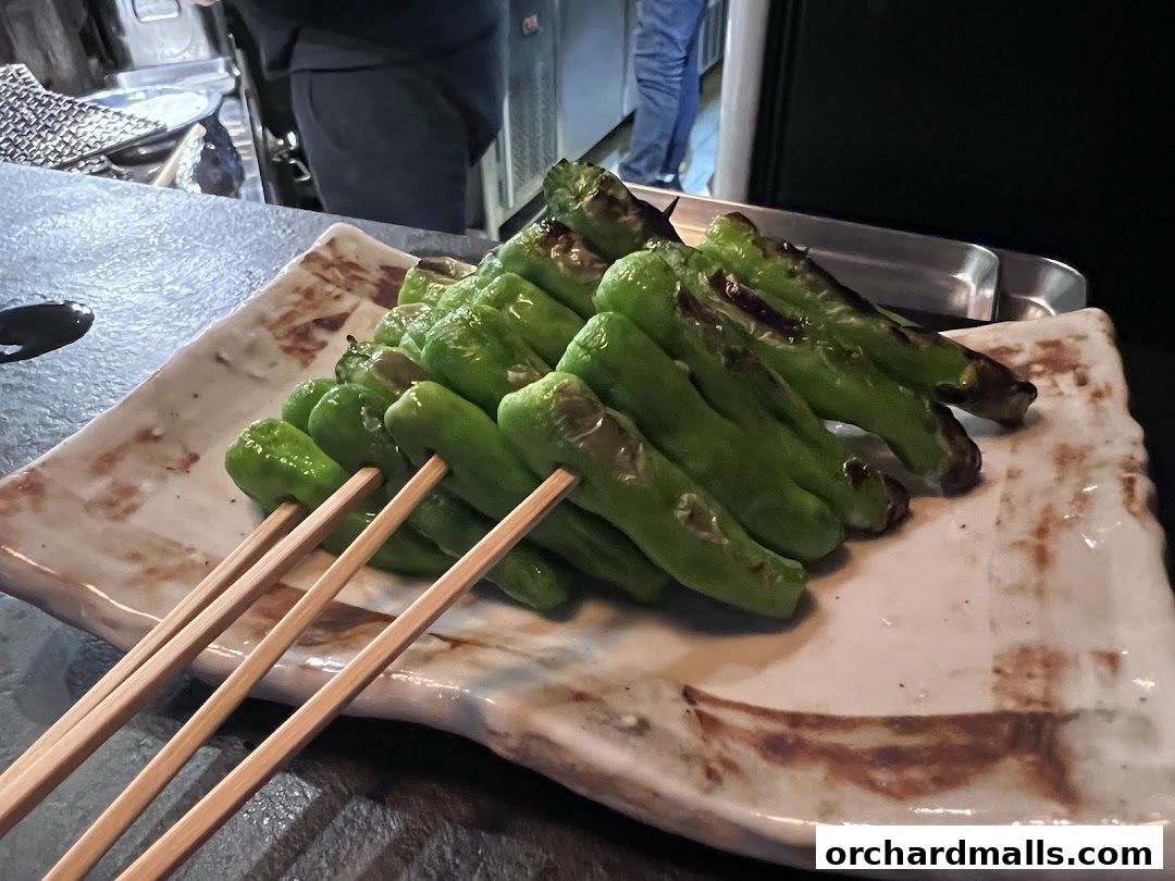 A plate of grilled green peppers on skewers, served at KAI Yakitori.