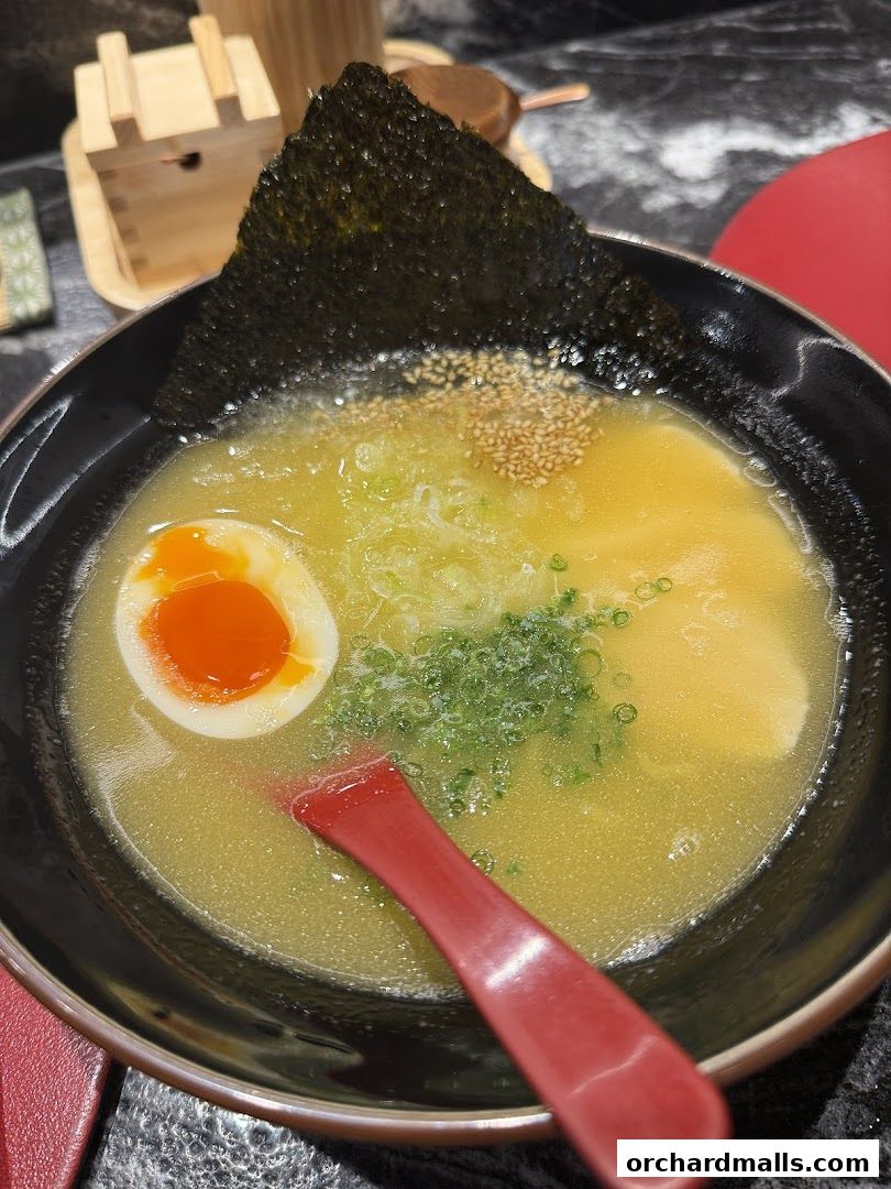 A close-up of a delicious bowl of ramen with a soft-boiled egg and nori.