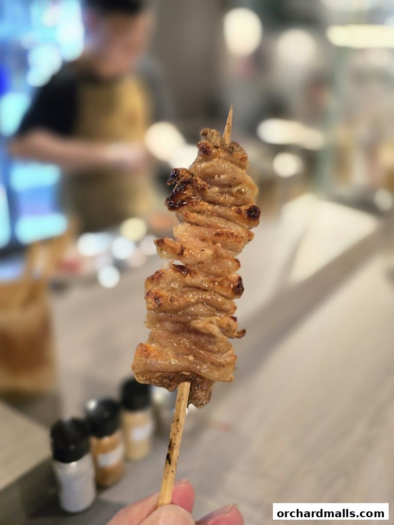 A close-up of a perfectly grilled yakitori skewer held by a hand.