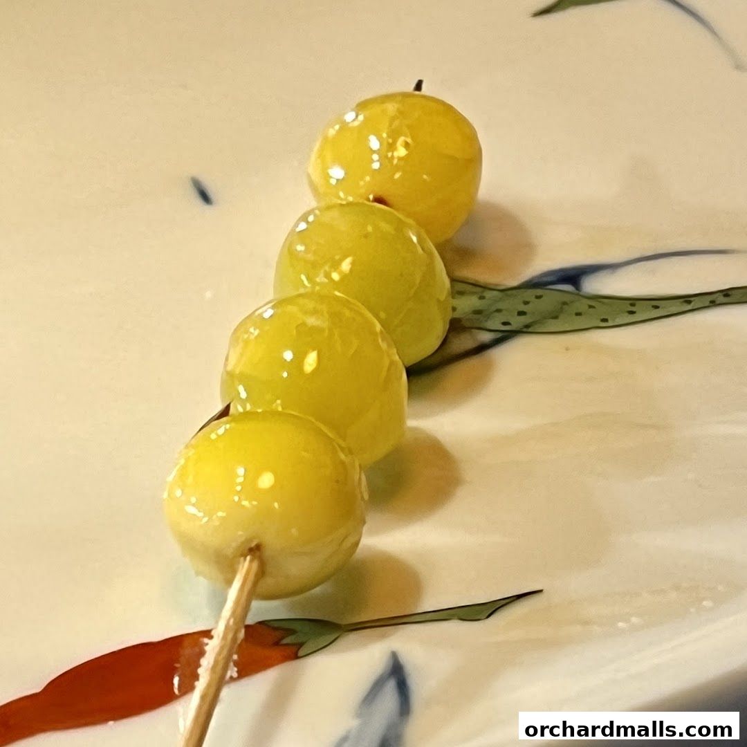 A skewer of glistening green grapes served on a decorative plate.