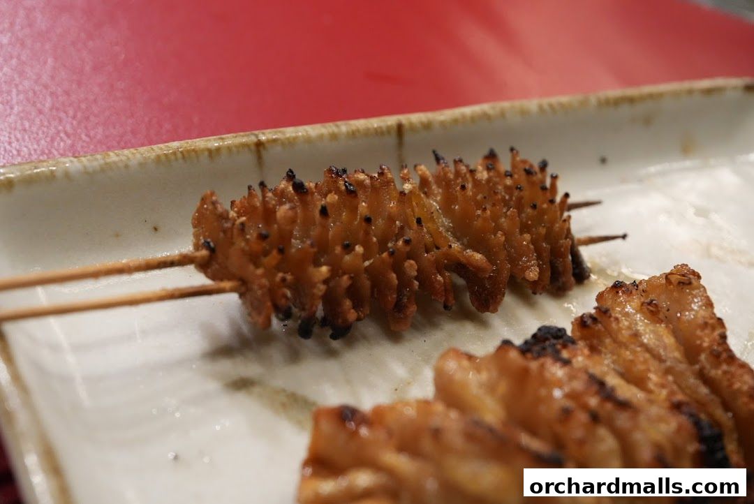 Close-up of grilled yakitori skewers on a plate with a red background.