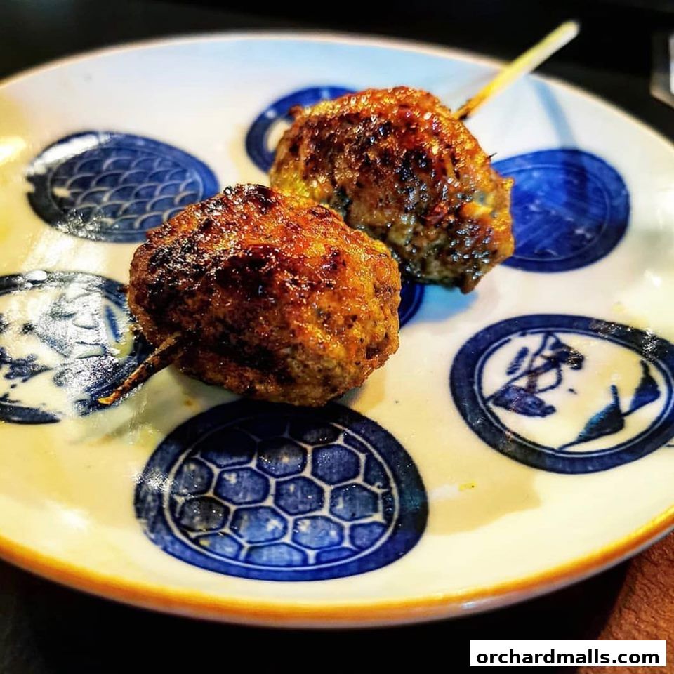Two delicious yakitori skewers with meatballs on a decorative plate.
