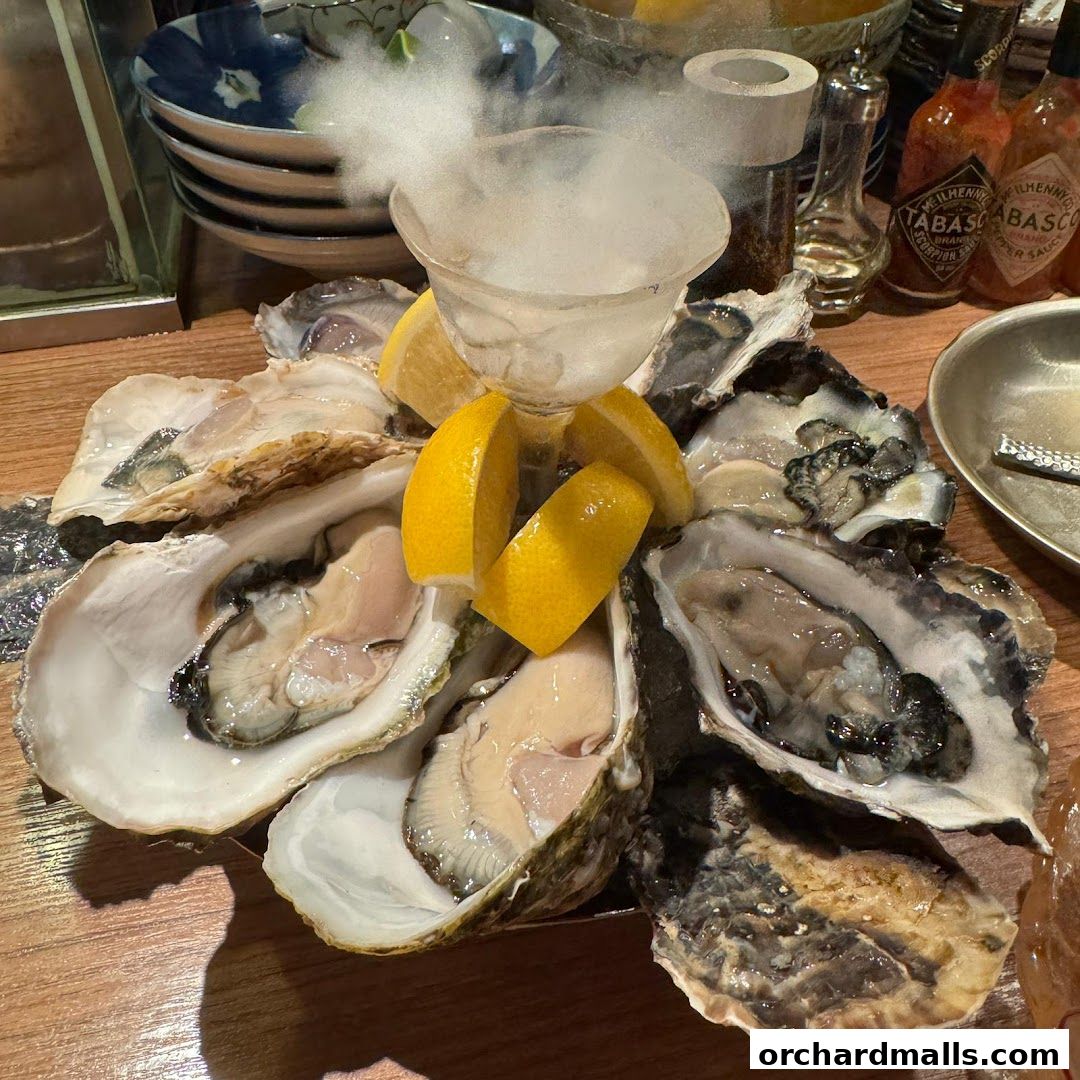 A platter of fresh oysters served with lemon wedges and a smoking ice bowl.