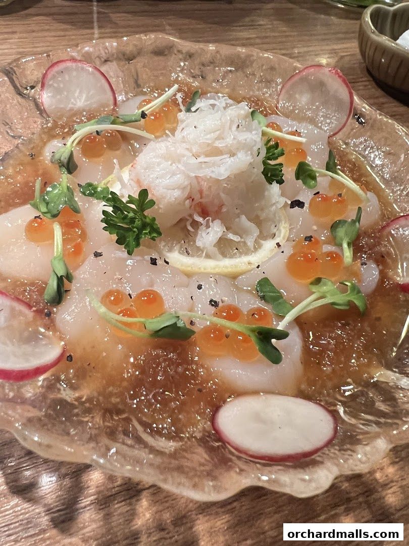 A beautifully plated scallop dish with roe, radish, and microgreens.