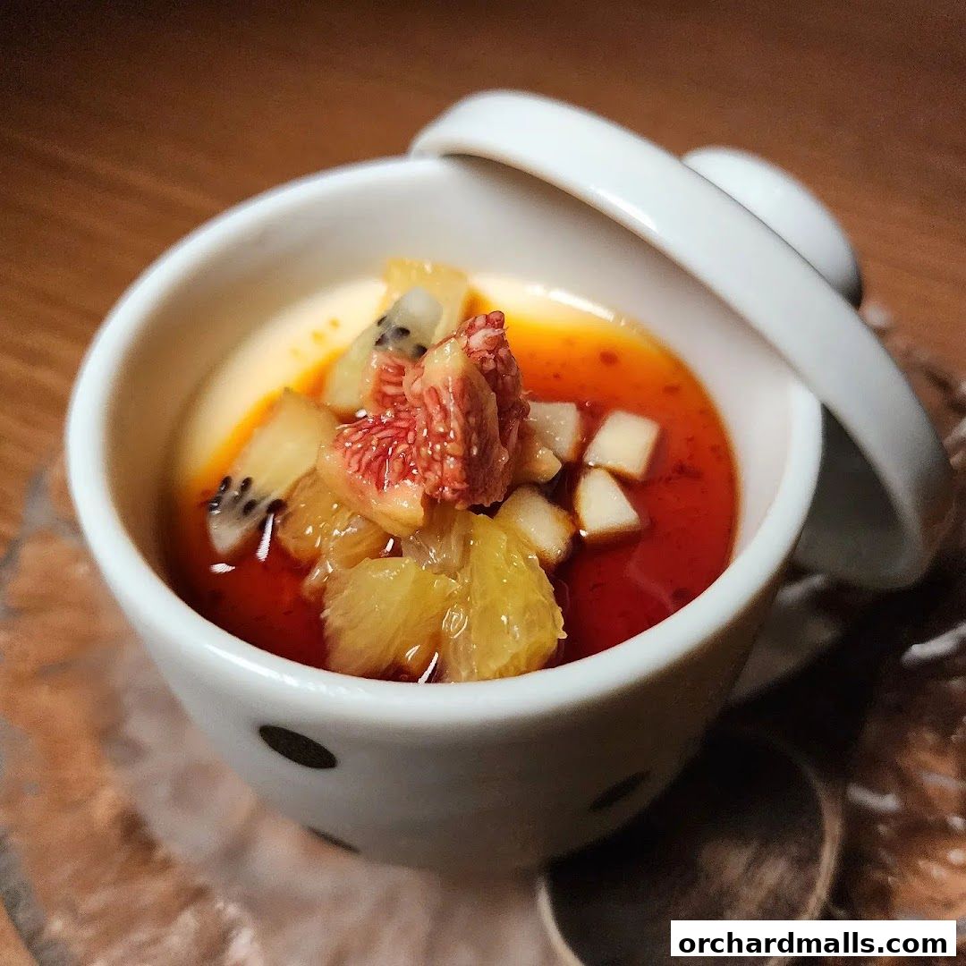 A white ceramic bowl filled with a creamy dessert topped with fresh fruits and a red syrup.