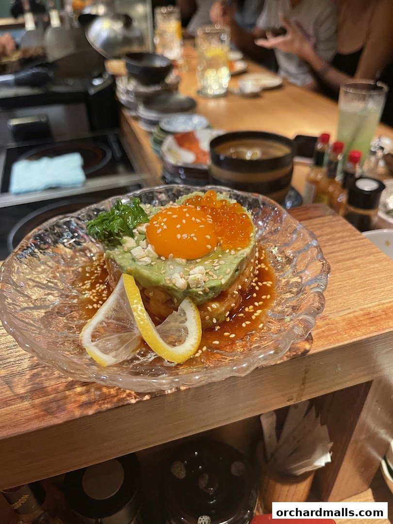 A beautifully presented avocado and egg dish with salmon roe and lemon slices.