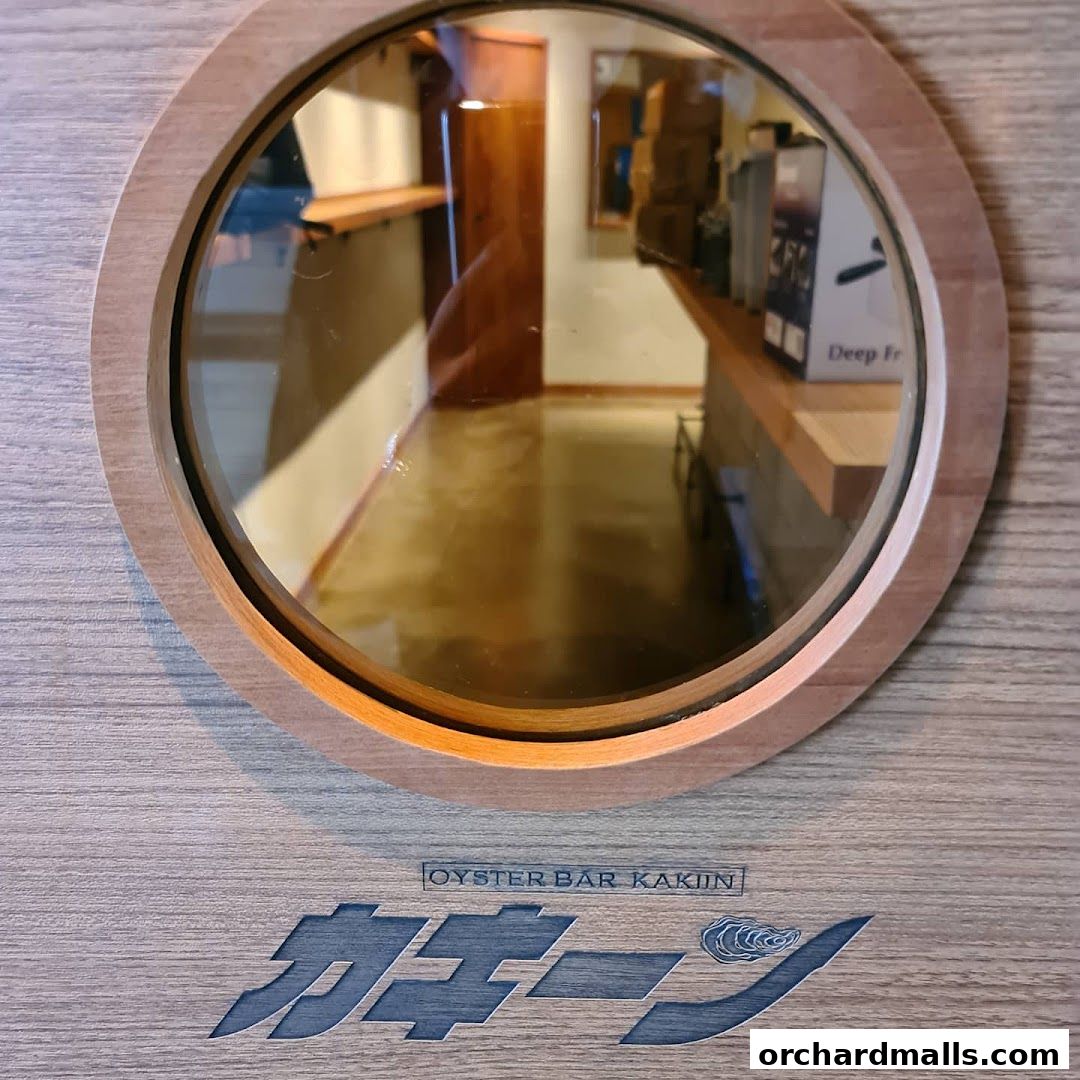A circular mirror reflects the interior of an oyster bar with wooden accents.
