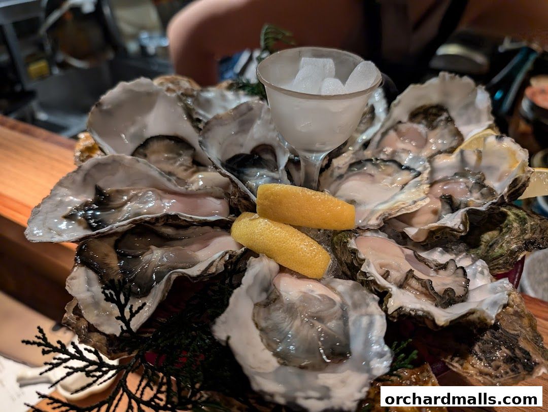 A close-up of a platter of fresh oysters served with lemon wedges and ice.