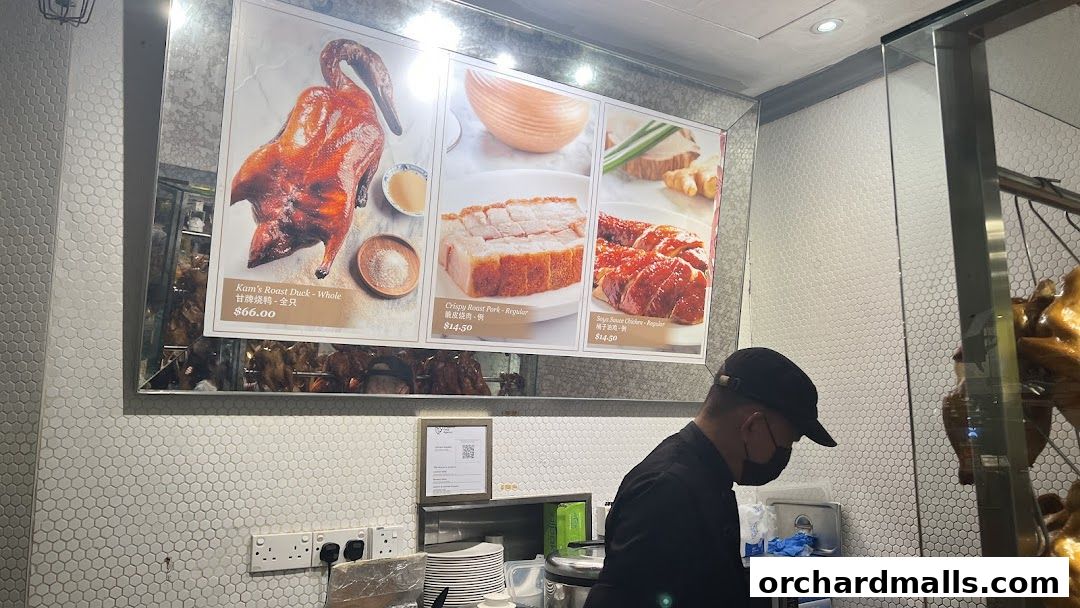 A display of roast duck, crispy pork, and soy sauce chicken with prices.