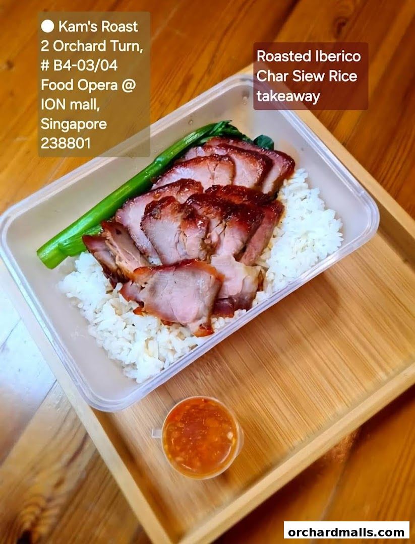 A takeaway container of roasted Iberico char siew rice with a side of chili sauce.