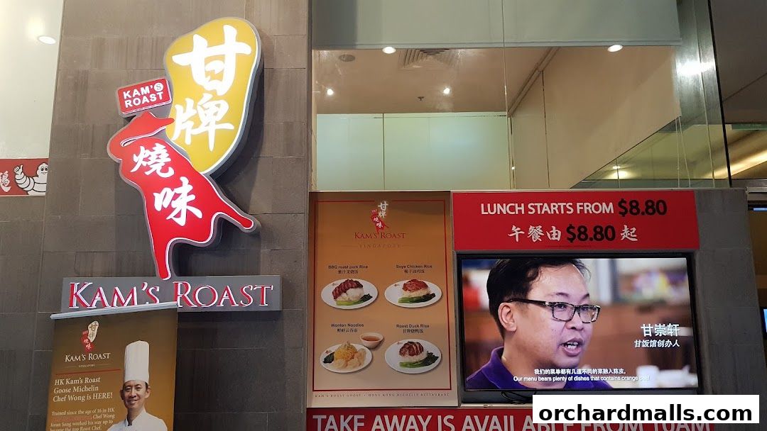 The exterior of Kam's Roast Express, featuring its prominent signage and a display of popular dishes.
