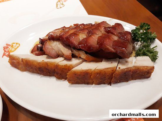 A plate of delicious roasted meats, including char siu and crispy pork belly, garnished with parsley.