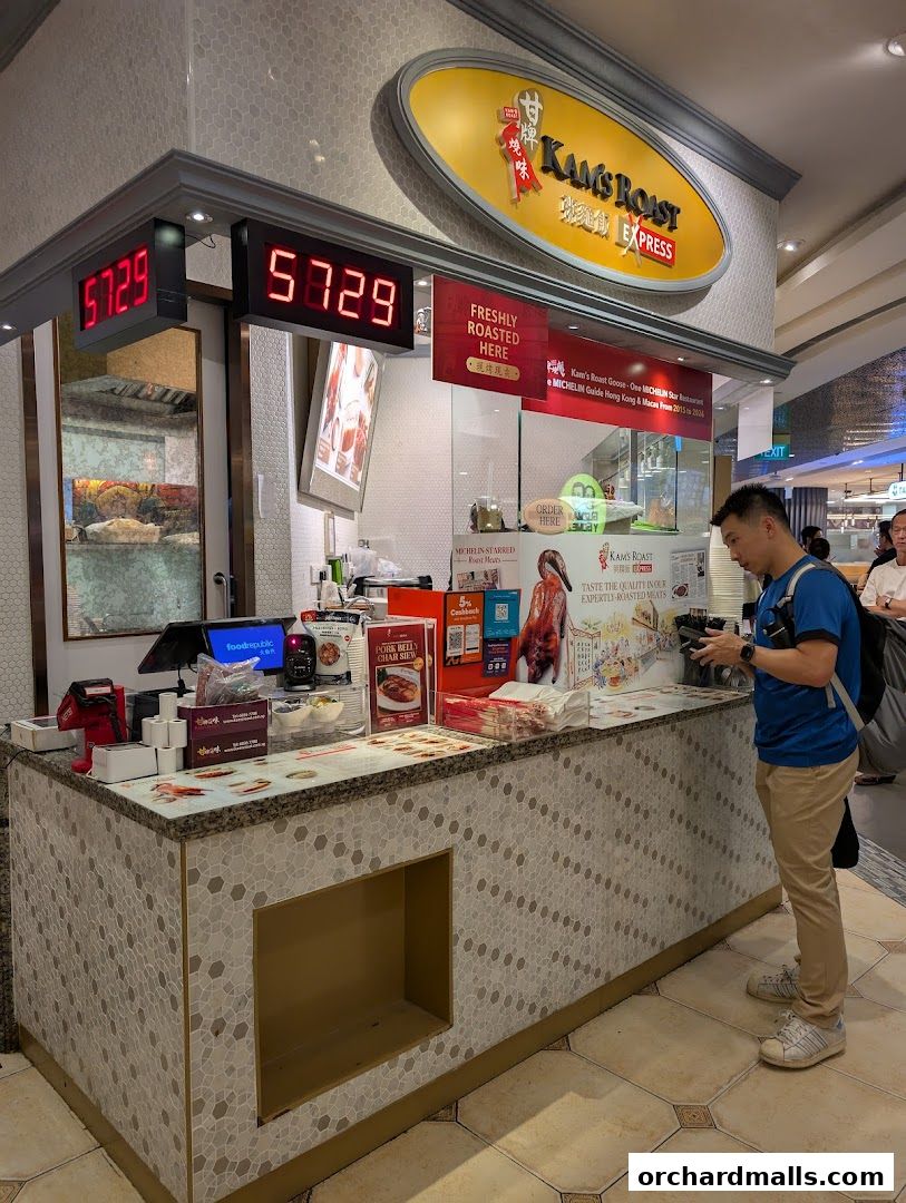 A customer stands at the counter of Kams Roast Express, a shop specializing in roasted meats.