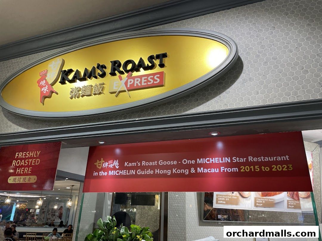 The exterior of Kam's Roast Express, featuring its prominent signage and a banner highlighting its Michelin star status.