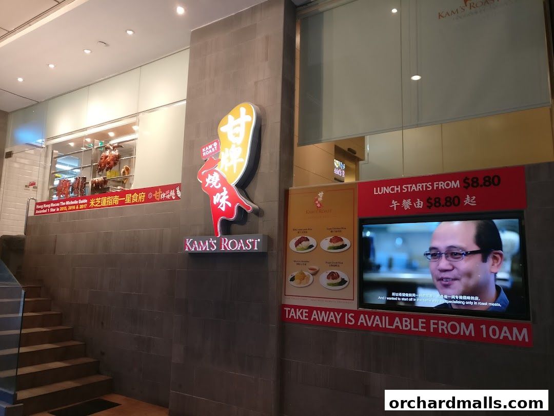 The exterior of Kam's Roast Express, featuring its logo, Michelin star awards, and a digital display.