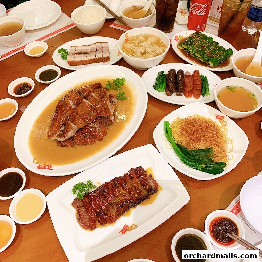 A table laden with various Chinese roasted meats, noodles, and side dishes.