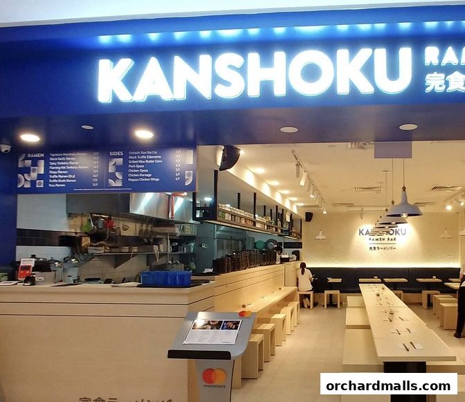 The entrance and interior of Kanshoku Ramen Bar, featuring a bright sign and seating area.