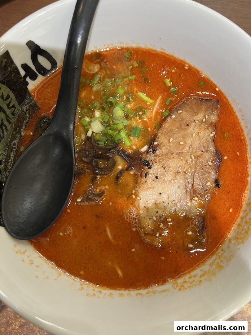 A close-up shot of a steaming bowl of ramen with rich broth, chashu pork, and green onions.