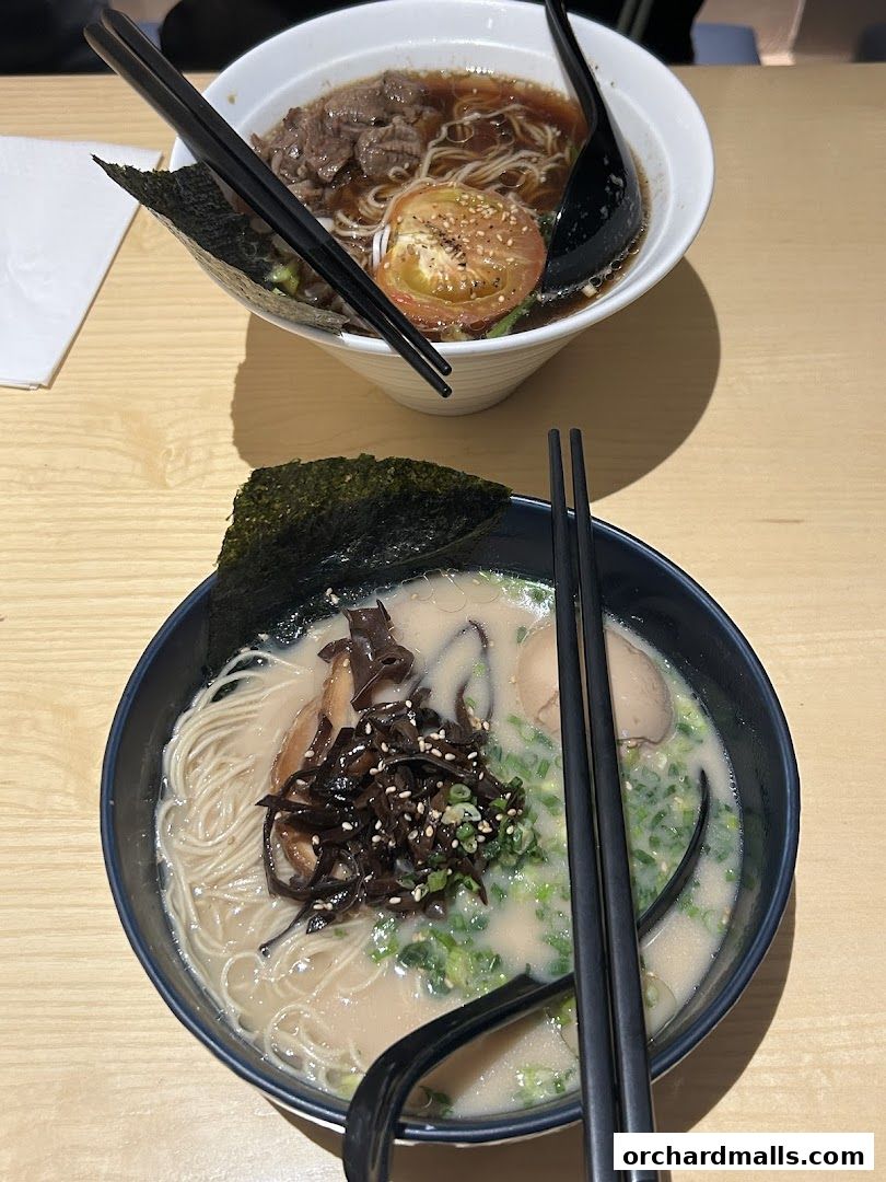 Two bowls of ramen, one with beef and tomato, the other with pork and mushrooms, are ready to be eaten.